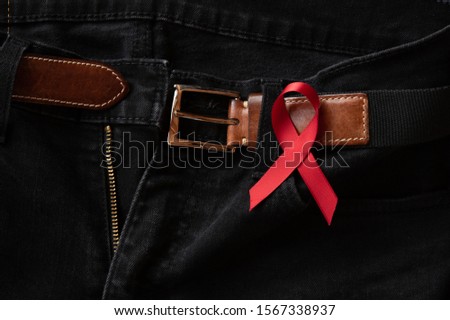 World Aids Day Concept. Belt on black jeans with red ribbon