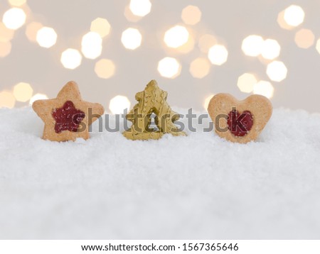 colourful christmas cookies on white snow with many small, shining lights in the background