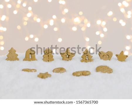 colourful christmas cookies on white snow with many small, shining lights in the background