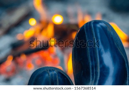 Rubber boots on the background of a tourist campfire. Close-up. Selective focus. Landscape photo arrangement.