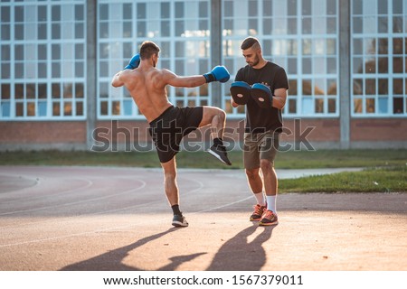 Two athletic young men boxing . Men training outdoors . Training kickboxing.Two males boxing outdoors. Sparring training box outside sport concept.  Royalty-Free Stock Photo #1567379011
