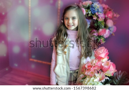 portrait of a happy girl next to vases with flowers in the interior, smiling child