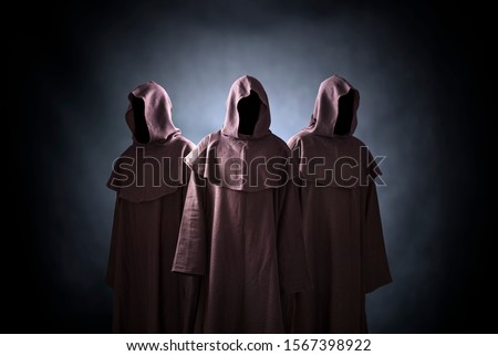 Group of three scary figures in hooded cloaks Royalty-Free Stock Photo #1567398922
