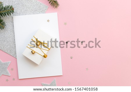 Flat lay New Year and Christmas ornaments background. Top view fir branches and gift box. Merry Christmas letter concept on a pink background