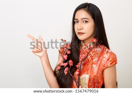 Young Asian woman in traditional chinese red dress with plum flowers , Chinese new year's and Lunar new year decoration for Spring festival isolated on light gray banner background 