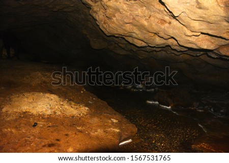 Close up of  Stalactite rock formation in the dark caves of Cherrapunjee and stream of water flowing down, also known as Sohra Plateau of Meghalaya, Shillong, selective focusing, low light