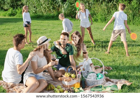 portrait of smiling people on picnic outdoors on background with kids playing active games