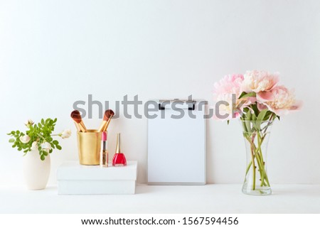 Home interior with decor elements. Mockup clipboard, pink peonies in a vase, cosmetic set