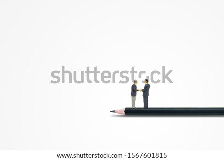 Business Concept : Businessmen standing on black pencil and they shaking hands together.