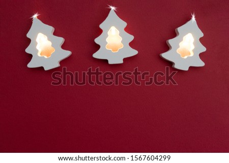 Christmas card with place for text. White wooden christmas tree with lanterns on a red background. The concept of a festive mood. Gift for 2020 New Year.