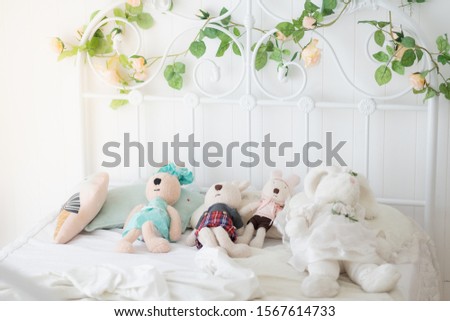 Four rabbit dolls lying down on the bed under sunlight with copy space. The bed was decorated with artificial leaf and flower