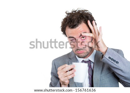 A close-up portrait of a very tired, falling asleep businessman holding a cup of coffee, struggling not to crash and stay awake, keeping his eyes opened, isolated on a white background with copy space