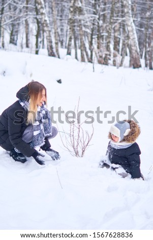 Mom and baby have fun in the snowy forest.  Winter vacations and outdoor games