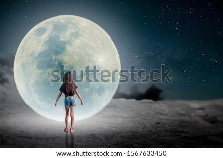 The little girl stood watching the moon on the desert on a beautiful night.