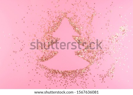 Christmas tree silhouette surrounded by gold confetti stars on a pink pastel background. Top view. Christmas card blank. Copy space and horizontal orientation.