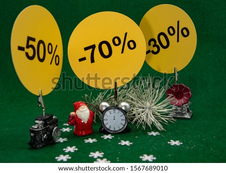 Small toy figures, Christmas decor with signs indicating the percentage of the sale on a green background. Christmas sale.