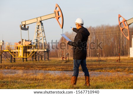 Engineer in a white helmet on an oil rig with a tablet. Oil production in Russia, Republic of Bashkortostan. Quality control