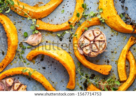 Baking tray with roasted pumpkin with garlic and herbs.