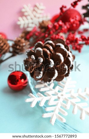 white snowflake, red Christmas tree decoration and fir cone on blue background