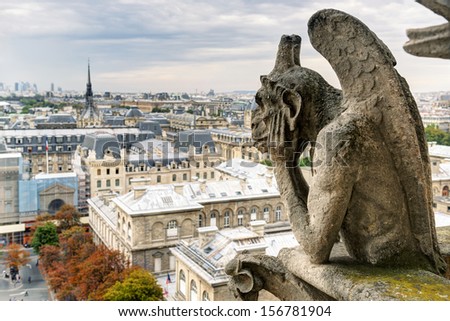 Chimera (gargoyle) statue of Notre Dame Cathedral overlooking Paris, France. Gothic French gargoyle on top of Dame church. Melancholy demon looks at city from above. Theme of thinking, travel, Dame.
