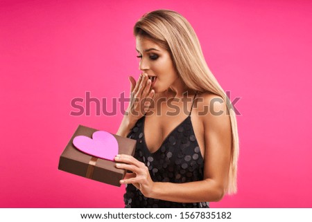 Beautiful adult woman posing over pink background with present