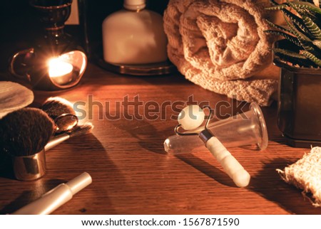 Luxurious jade massager and facial massage jar. Composition of massager and massage jar from aging on the women's table. The concept of natural skin care. Stock photo.