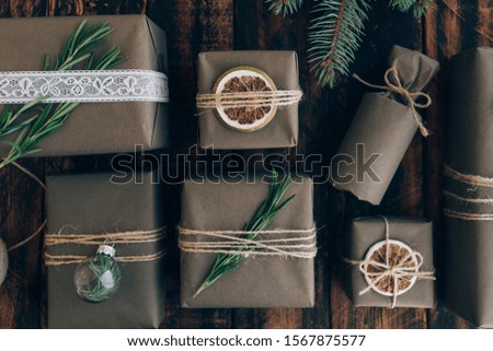 Presents and gifts wrapped in craft paper with decoration on brown wooden background. Flat lay, close up. Holiday zero waste concept.