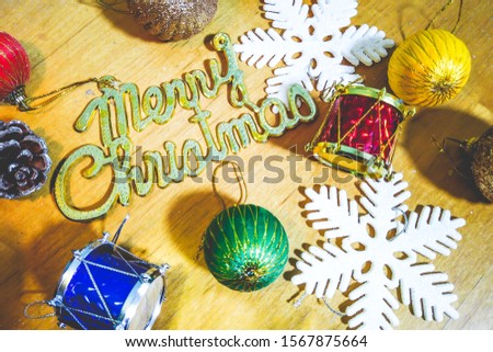Blurred picture of Christmas background with Merry Christmas sign surrounded by ornaments on wooden surface. Festive background