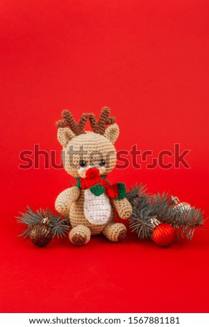 Hand-made toy christmas deer, spruce twigs and christmas balls on red background.Christmas concept. Vertical orientation