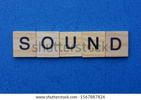 word sound made from brown wooden letters lies on a blue table