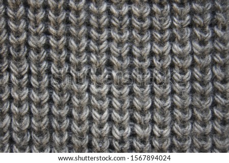 Grey handmade knitted pearl rib. Soft woolen scarf closeup photo. Horizontal wallpaper. Elegant fabric cloth backdrop with empty space