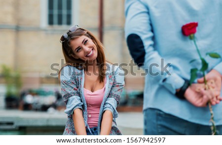 Dating. Young man surprised his girlfriend with a red rose. Love and relationships Royalty-Free Stock Photo #1567942597