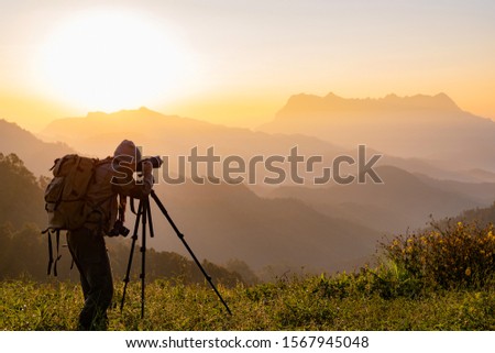 Nature photographer take photos with mirror camera on peak of mountain at morning sunrise
