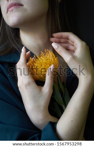Portrait of an artistic girl hands hold an orange protea, selective focus