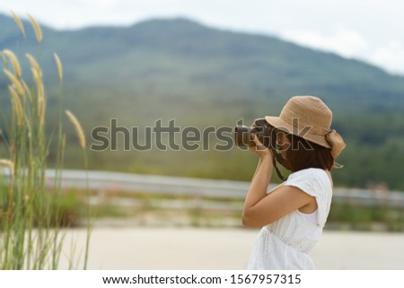 Beautiful asian travel woman with camera sit,relax in nature.moutain and grass around herself.