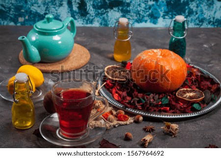 Red Hot Hibiscus tea in a glass mug on a wooden table among rose petals and dry tea custard with carcade