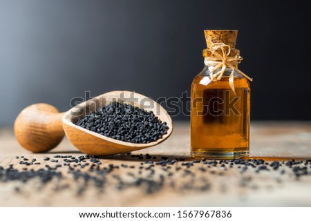 glass bottle of black cumin seeds essential oil , Nigella Sativa in spoon on wooden background. Organic herbal medicine for many diseases, black cumin Royalty-Free Stock Photo #1567967836