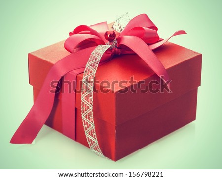 Red gift box tied with a decorative bow for celebrating Christmas, Valentines, birthday or an anniversary on a pale green background