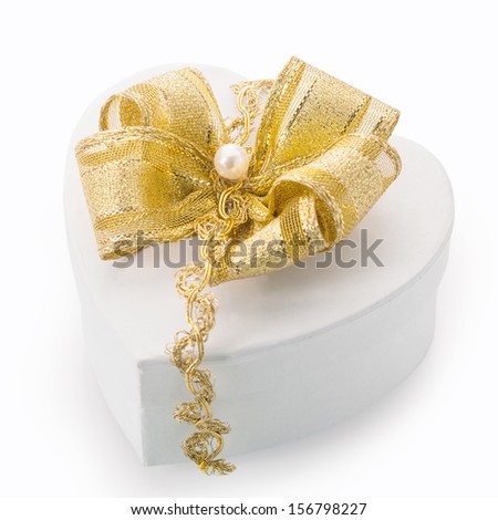 Heart shaped white cardboard gift box tied with an elegant gold bow, braid and pearl for surprising a loved one on Christmas, Valentines, birthday or an anniversary
