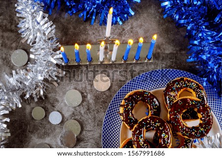Hanukkah background. Menorah with burning candles, donuts and chocolate coins with hanukkah decoration.