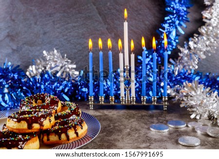 Hanukkah menorah, donuts, chocolate coins and white and blue decoration.