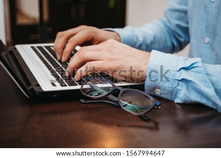 Business man typing hands on laptop with glasses on the desk in the office