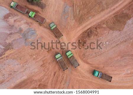 Aerial shot of multiple large trucks pulling dirt on construction site top view