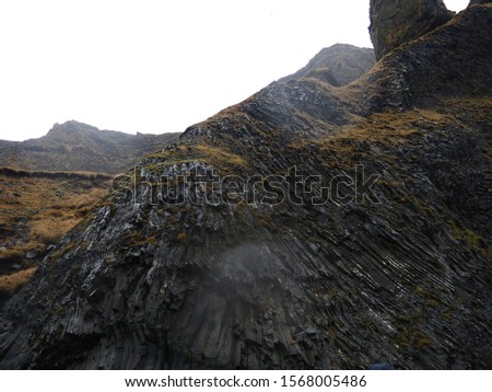 A cliff of a South Icelandic sea coast on a rainy day, Reynisfjara, Iceland, steep cliff, basalt rock formation