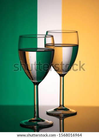 Two wine glasses silhouette full on irish flag background. Alcohol beverage. Irish wine concept. Flag of Ireland Royalty-Free Stock Photo #1568016964
