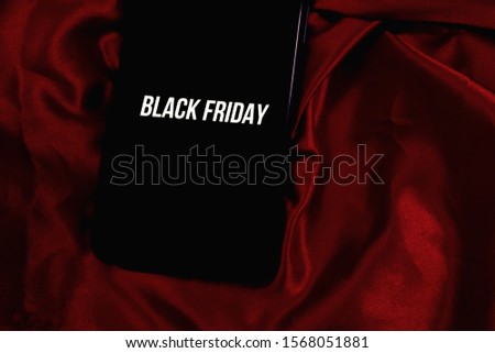 Smart phone on red background with the words "BLACK FRIDAY" event held on the end of November.