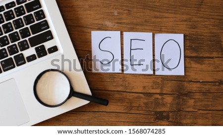 SEO (Search Engine Optimization) Text and magnifying glass on wood table background