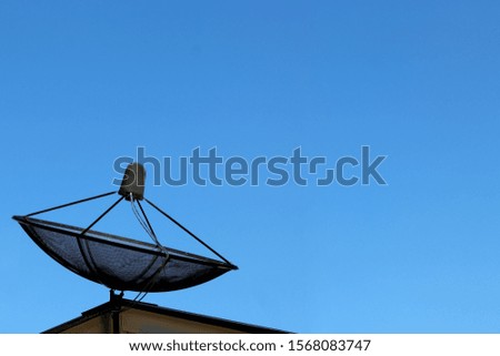 Black network satellite disc on roof on blue sky background