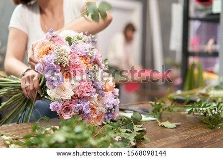 European floral shop concept. Florist woman creates beautiful bouquet of mixed flowers. Handsome fresh bunch. Education, master class and floristry courses. Flowers delivery. Royalty-Free Stock Photo #1568098144