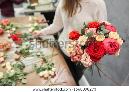 Step by step florist woman creates red beautiful bouquet of mixed flowers. Handsome fresh bunch. Education, master class and floristry courses. Flowers delivery. European floral shop concept. Royalty-Free Stock Photo #1568098273